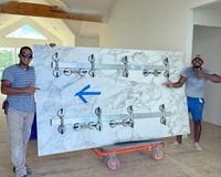 Team Carrying a High-Quality Marble Slab: Two professional installers smiling while holding a polished marble slab with a detailed veining pattern, highlighting craftsmanship and precision in luxury home projects.