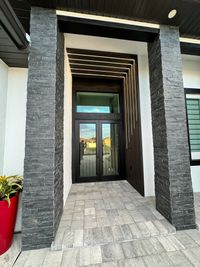 Elegant Entrance with Stone Pillars and Modern Design
A modern entrance featuring textured stone pillars, sleek black glass doors, and layered wooden slats with integrated LED lighting, perfect for upscale architectural aesthetics.