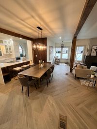 Open Concept Dining Room with Warm Wood Accents
A spacious dining area featuring natural wood floors, wooden accent walls, and a modern chandelier, seamlessly blending rustic charm with contemporary design.