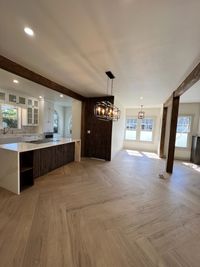 Bright and Open Kitchen with Natural Wood Flooring
A stylish kitchen and dining area with natural wood flooring, exposed wooden beams, and modern lighting, offering a warm and inviting atmosphere for gatherings.