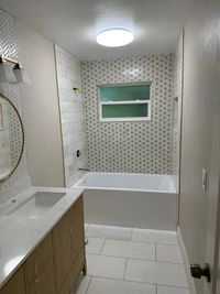 Elegant Bathroom with Patterned Accent Wall and Soaking Tub: A stylish bathroom featuring a white soaking tub, patterned wall tiles with geometric designs, and a serene ambiance for a modern yet cozy vibe.