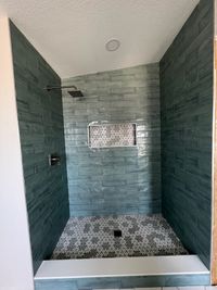Modern Shower with Blue Subway Tiles and Patterned Floor: A vibrant shower design featuring glossy blue subway tiles, a niche with decorative mosaic, and a floral-patterned tile floor for a bold statement.