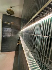 Contemporary Shower with Textured Green Tiles and Gold Accents: A luxurious shower with textured green tiles, recessed lighting, and brass rain shower fixtures for a sophisticated and modern look.