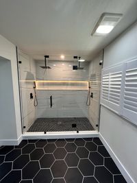 Modern Shower with Black Hexagon Tiles and Ambient Lighting: A glass-enclosed shower with black hexagon tiles, illuminated by sleek ambient lighting, for a stylish, modern bathing experience.