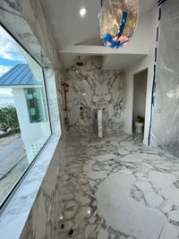 Marble Bathroom with Scenic View and Modern Fixtures: An opulent bathroom featuring floor-to-ceiling marble, large windows with scenic views, and contemporary fixtures for a luxurious retreat.