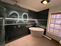 Double Vanity with Brass Fixtures and Chevron Tiles: A double vanity setup with gold-framed mirrors, brass light fixtures, and white herringbone-patterned tiles for a luxurious yet minimalist look.